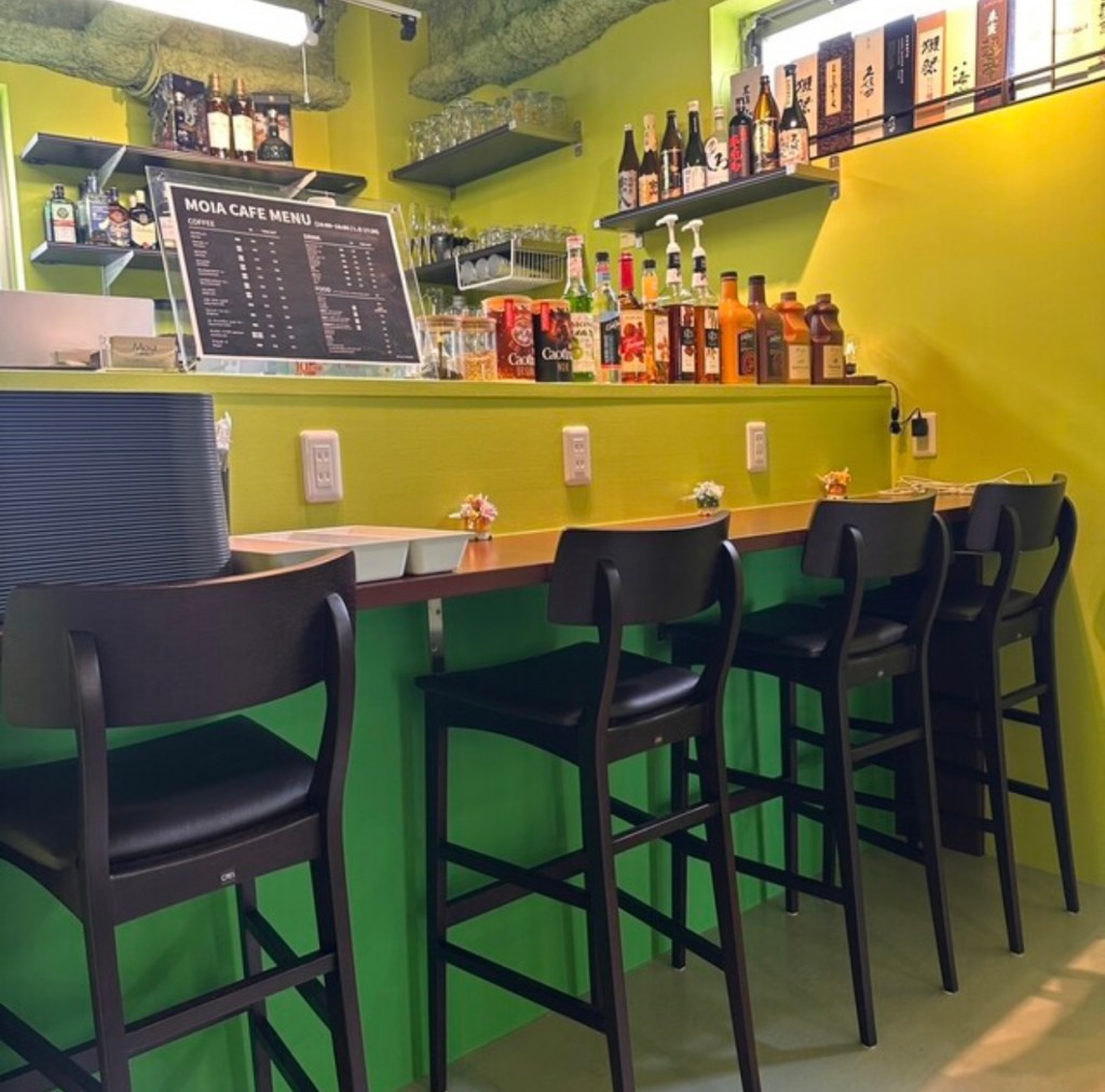 모이아 한국요리 Cafe&Bar의 내부 모습, 녹색 벽과 바 테이블이 있는 아늑한 카페 환경